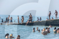 Sunbathers and swimmers on Brighton beach East Sussex, UK.