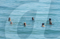 Sunbathers and swimmers on Brighton beach East Sussex, UK.
