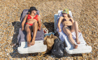 Sunbathers and swimmers on Brighton beach East Sussex, UK.