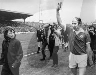 Sir Bobby Charlton waves to the crowd at the end of his last match when his team Manchester United.