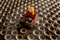 FEATURE - Töpfer sitzen umgeben von ihren Keramiken und polieren sie 