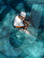 FEATURE - Ein Fischer sitzt umgeben von einem Meer von Netzen