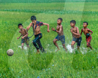 FEATURE -  Eine Gruppe von Kindern spielt auf überfluteten Feldern Fussball in Bangladesh