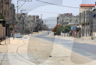 Palestinians walk in the sun along a street in the eastern part of Rafah in the southern Gaza Strip