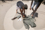 Palestinian youth lose some equipment and empty ammunition left by the Israeli army in along a street in the western part of Rafah