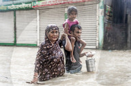 FEATURE - Eine Familie watet durch hüfthohes Wasser nach den Überschwemmungen in der südöstlichen Stadt Feni, Bangladesch