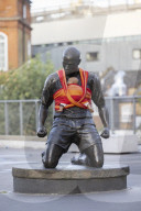 Campaigners tie baby slings to statues in call for better UK paternity leave.