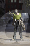 Campaigners tie baby slings to statues in call for better UK paternity leave.