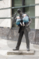 Campaigners tie baby slings to statues in call for better UK paternity leave.
