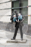 Campaigners tie baby slings to statues in call for better UK paternity leave.