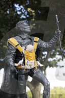 Campaigners tie baby slings to statues in call for better UK paternity leave.