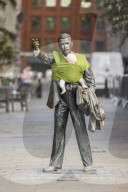 Campaigners tie baby slings to statues in call for better UK paternity leave.