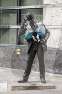 Campaigners tie baby slings to statues in call for better UK paternity leave.