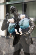 Campaigners tie baby slings to statues in call for better UK paternity leave.