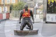 Campaigners tie baby slings to statues in call for better UK paternity leave.