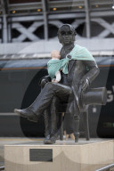 Campaigners tie baby slings to statues in call for better UK paternity leave.
