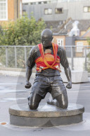 Campaigners tie baby slings to statues in call for better UK paternity leave.