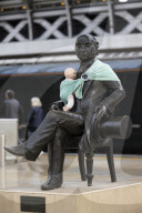 Campaigners tie baby slings to statues in call for better UK paternity leave.