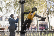 Campaigners tie baby slings to statues in call for better UK paternity leave.