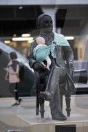 Campaigners tie baby slings to statues in call for better UK paternity leave.