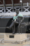 Campaigners tie baby slings to statues in call for better UK paternity leave.