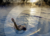 Swimmers brave cold temperatures to exercise in Hampton outdoor heated pool in south west London, UK. 