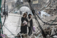 Palestinians walk through rubble during severe weather conditions in the Al-Rimal neighborhood in central Gaza City