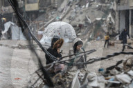 Palestinians walk through rubble during severe weather conditions in the Al-Rimal neighborhood in central Gaza City