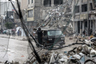 Palestinians walk through rubble during severe weather conditions in the Al-Rimal neighborhood in central Gaza City