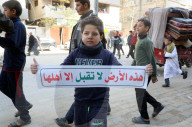Palestinians including children, holding banners, gather in front of the Suheda Mosque to protest against U.S. President Donald Trump's