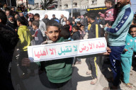 Palestinians including children, holding banners, gather in front of the Suheda Mosque to protest against U.S. President Donald Trump's