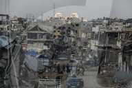 Palestinians walk past the rubble of destroyed buildings, amid a ceasefire between Israel and Hamas, in the Zeitoun neighborhood, south of Gaza City