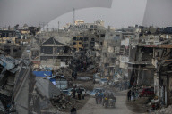 Palestinians walk past the rubble of destroyed buildings, amid a ceasefire between Israel and Hamas, in the Zeitoun neighborhood, south of Gaza City