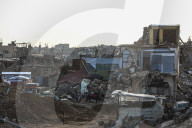 Palestinians walk past the rubble of destroyed buildings, amid a ceasefire between Israel and Hamas, in the Zeitoun neighborhood, south of Gaza City