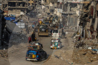 Palestinians walk past the rubble of destroyed buildings, amid a ceasefire between Israel and Hamas, in the Zeitoun neighborhood, south of Gaza City