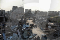 Palestinians walk past the rubble of destroyed buildings, amid a ceasefire between Israel and Hamas, in the Zeitoun neighborhood, south of Gaza City