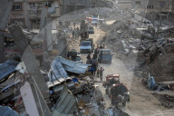 Palestinians walk past the rubble of destroyed buildings, amid a ceasefire between Israel and Hamas, in the Zeitoun neighborhood, south of Gaza City