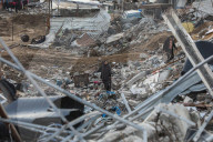 Palestinians walk past the rubble of destroyed buildings, amid a ceasefire between Israel and Hamas, in the Zeitoun neighborhood, south of Gaza City