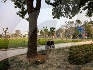 Two Women In Conical Hats Rest On A Bench In A Park In Vietnam