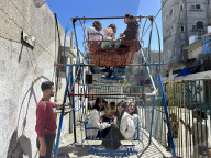 Gaza children playing amidst tents and rubble