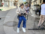 Gaza children playing amidst tents and rubble