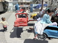 Gaza children playing amidst tents and rubble