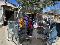 Gaza children playing amidst tents and rubble