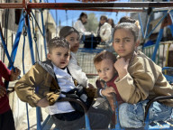 Gaza children playing amidst tents and rubble