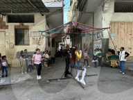 Gaza children playing amidst tents and rubble