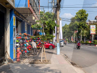 Man Browses Motorcycle Helmets At Sidewalk Stall