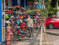 Man Browses Motorcycle Helmets At Sidewalk Stall