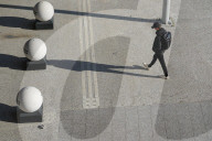 A Young Man Walking Across Sunlit Plaza