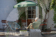 Senior Man Relaxing At A Shaded Café Corner