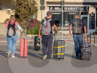 Travelers With Luggage Walking Along Street